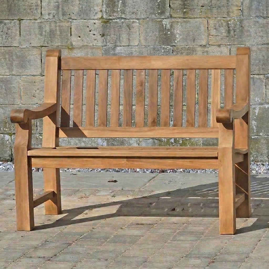 FSC 2 seat Teak Wooden garden bench in front of a stone wall