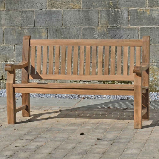 FSC 3 seat Teak Wooden garden bench in front of a stone wall