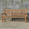 FSC 4 seat Teak Wooden garden bench in front of a stone wall