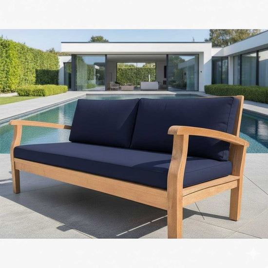 Wooden outdoor sofa with navy cushions by a poolside.