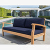 Wooden outdoor sofa with navy cushions by a poolside.