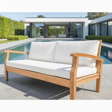 Wooden outdoor sofa with white cushions on a patio area.