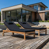 Two wooden outdoor sun loungers with wheels and black cushions on wooden decking
