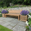 Wooden bench in a garden setting with lavender plants and stone pathway.