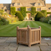 Wooden planter box on a stone patio with a garden and house in the background