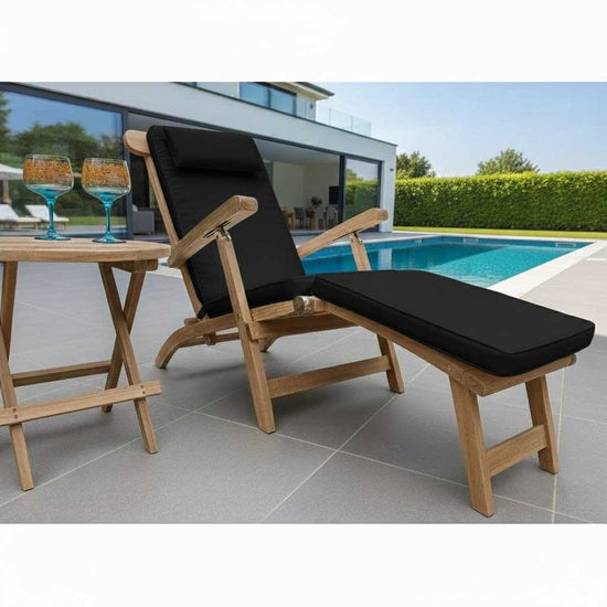Wooden lounge steamer chair with luxury black cushion next to a poolside table with drinks.