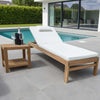Wooden sun lounger chair with white cushion next to a poolside table with wine glasses and a bottle.