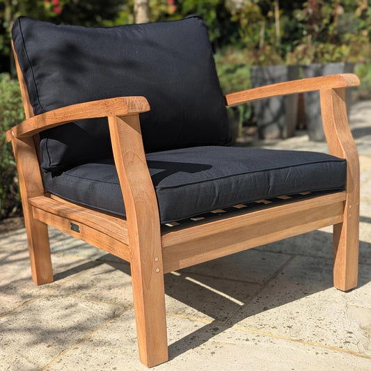 Wooden outdoor chair with black cushions on a stone patio