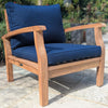 Wooden outdoor chair with blue cushions on a stone patio