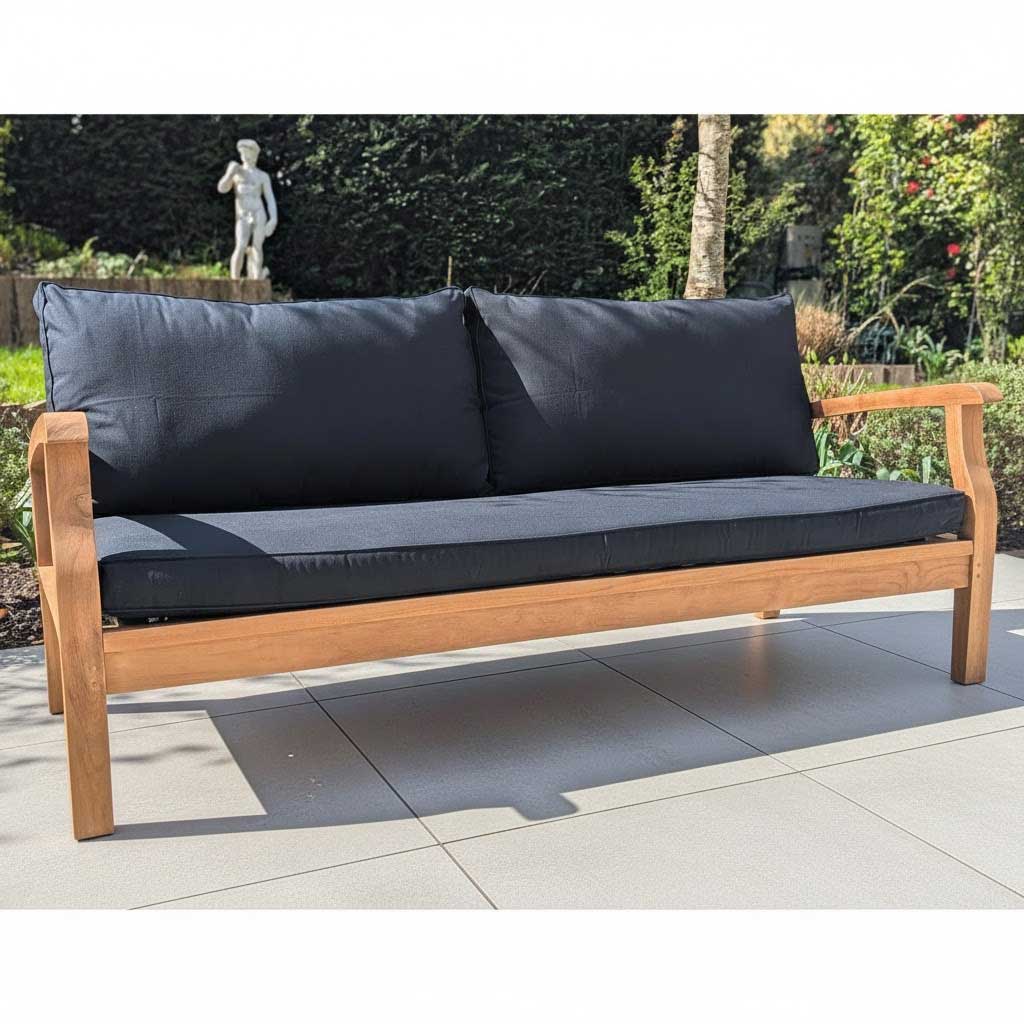Wooden outdoor sofa with dark cushions on a stone patio