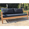Wooden outdoor sofa with dark cushions on a stone patio