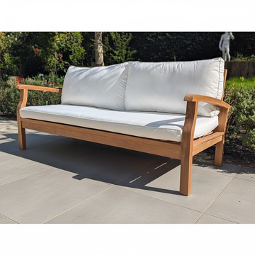 Wooden outdoor sofa with white cushions on a grey patio