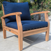 Wooden outdoor day bed chair with blue cushions on a grey patio