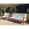 Wooden outdoor sofa set with white cushions in a garden setting