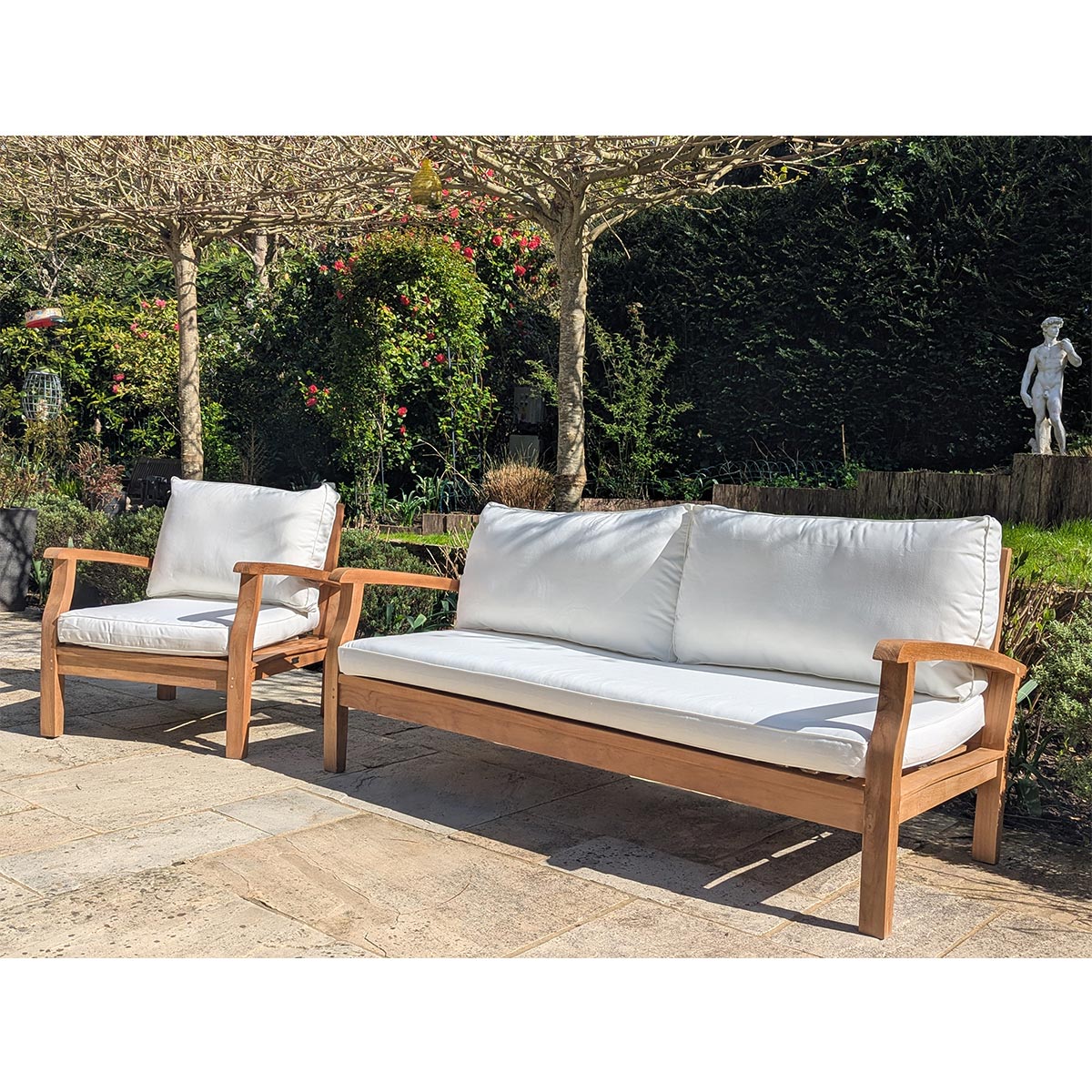 Wooden outdoor sofa set with white cushions in a garden setting