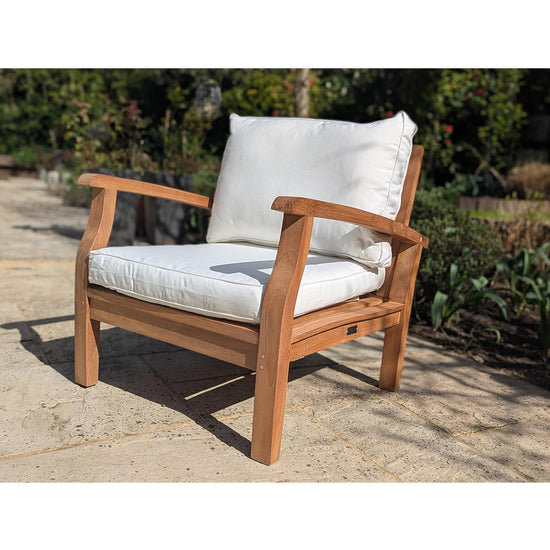 Wooden chair with white cushions on a stone patio