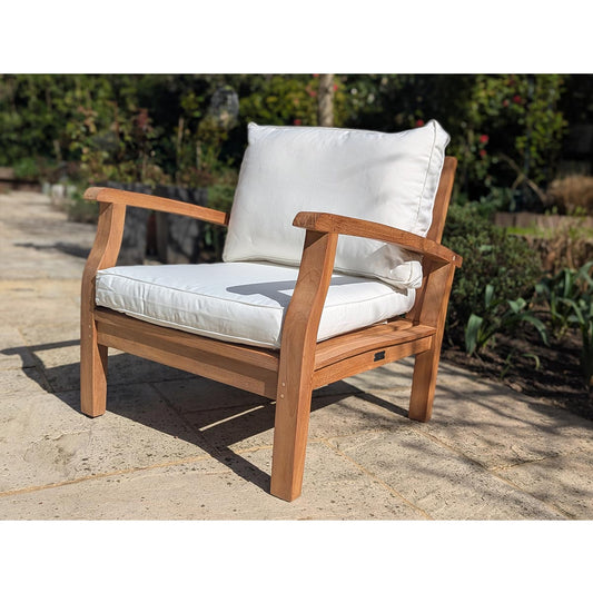Wooden chair with white cushions on a stone patio