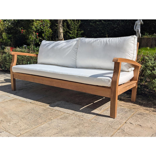 Wooden outdoor sofa with white cushions on a stone patio