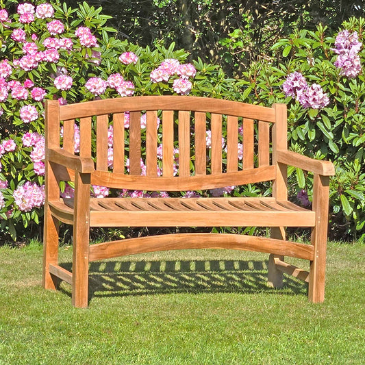 garden bench with an oval back in a garden setting with purple flowers in the background