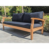 Wooden outdoor sofa with dark cushions on a stone patio