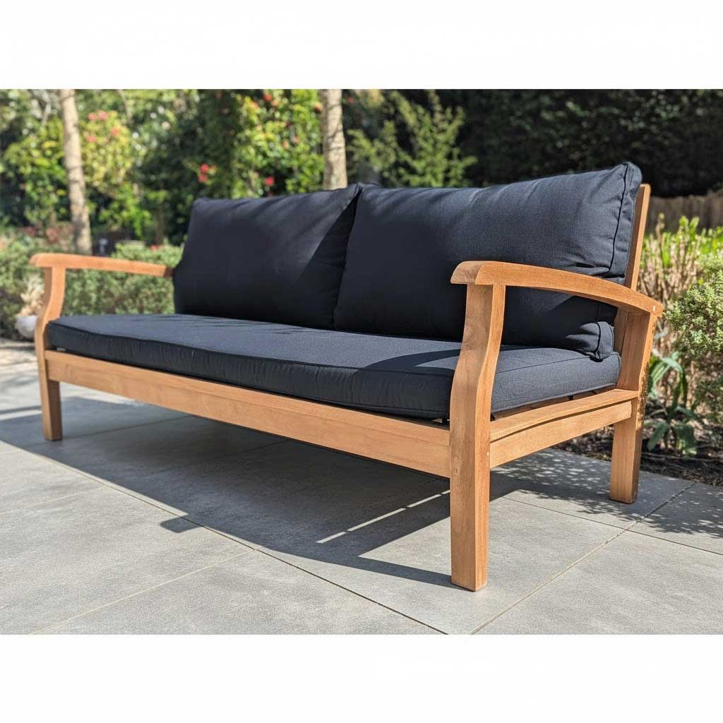 Wooden outdoor sofa with dark cushions on a stone patio