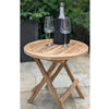 Wooden round folding table with two wine glasses and a bottle on a patio