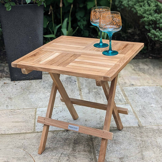 Wooden square folding coffee table with two glasses on a patio