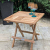Wooden square folding coffee table with two glasses on a patio