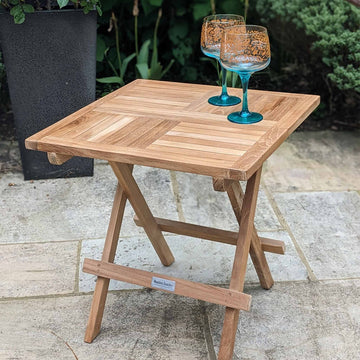 Wooden square folding coffee table with two glasses on a patio