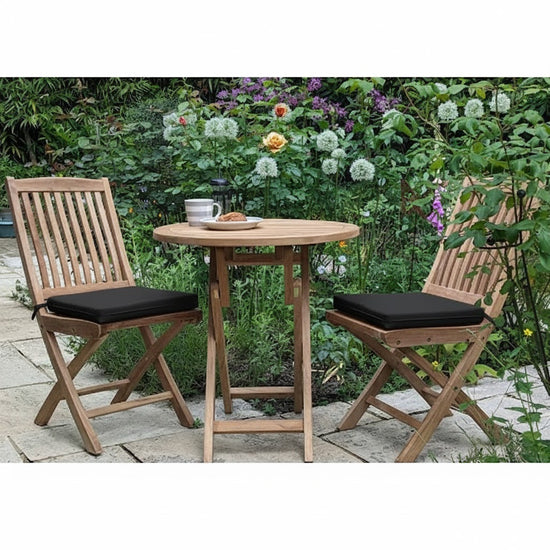 teak balcony dining furniture set on a paved floor with plants in the background