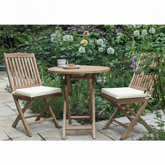 teak garden bistro set on a patio with plants in the background