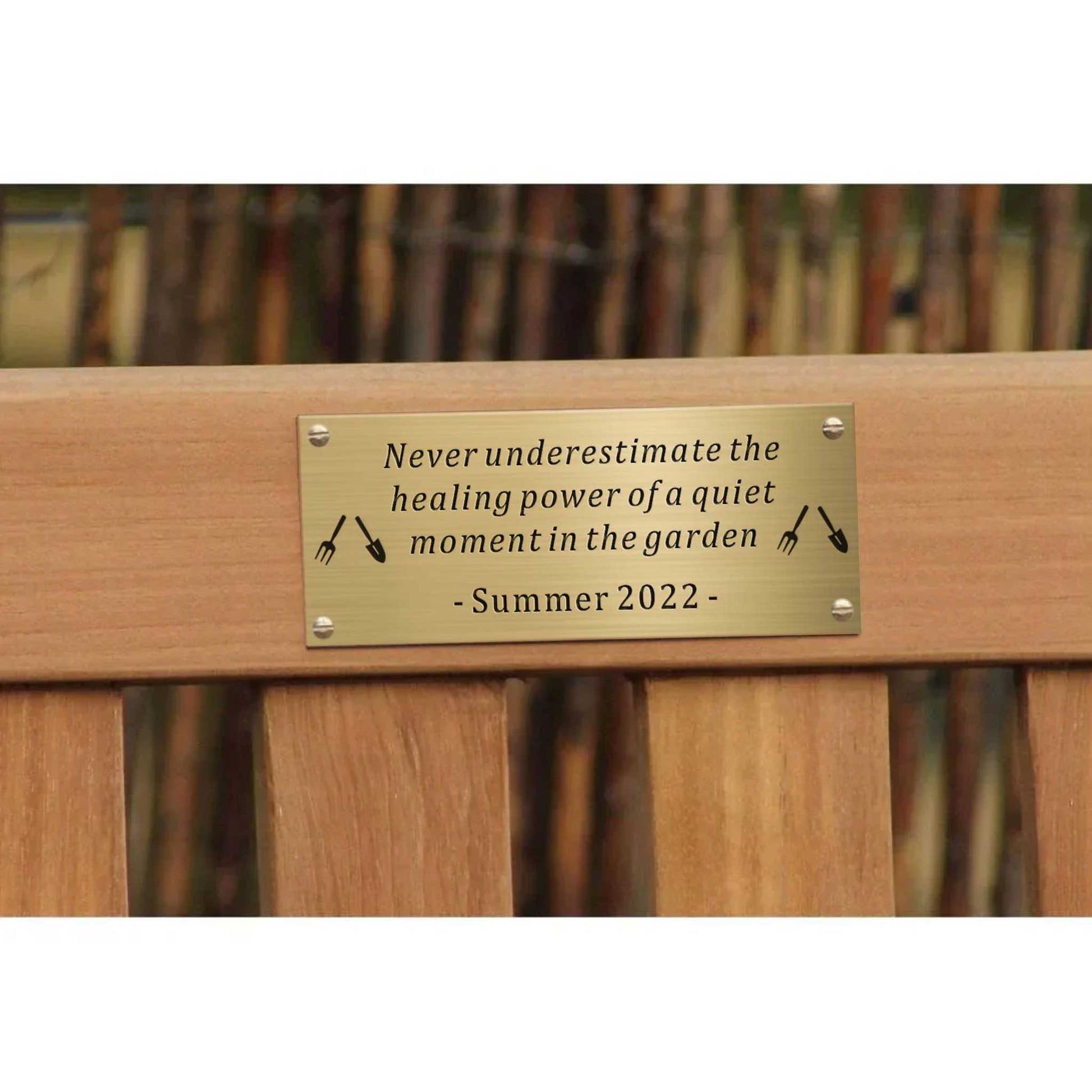 Wooden bench with a brass plaque featuring a quote about the healing power of a quiet moment in the garden, set against a blurred garden background.