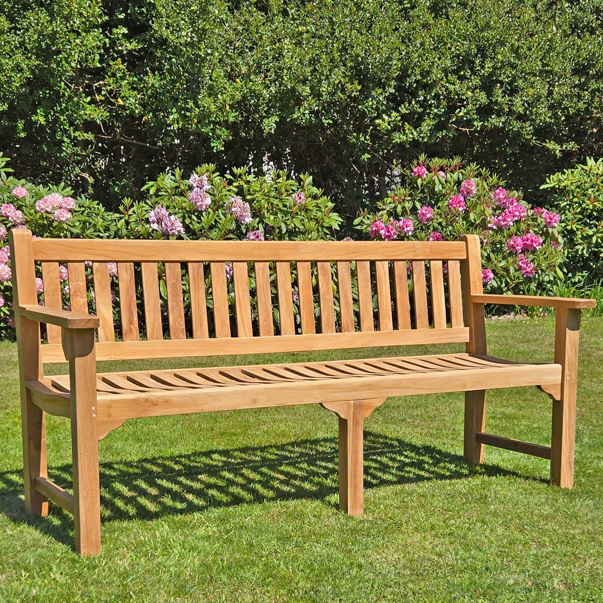 Wooden teak garden bench, 4 seat Farleigh, in a garden setting on a lawn