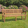large 4 seat teak garden bench, Sandhurst, with scroll arms in a garden setting 