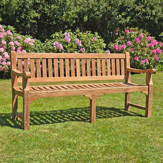 large 4 seat teak garden bench, Sandhurst, with scroll arms in a garden setting 