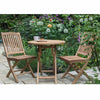Teak outdoor bistro style table with two chairs, on a patio area
