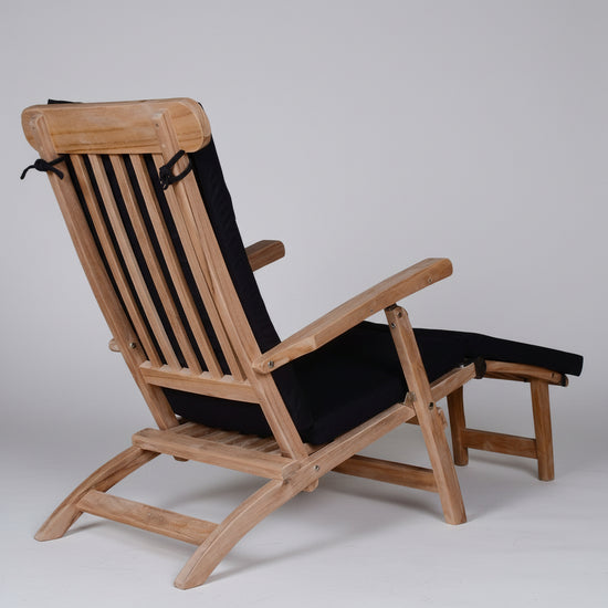 Wooden steamer chair with black cushions on a white background