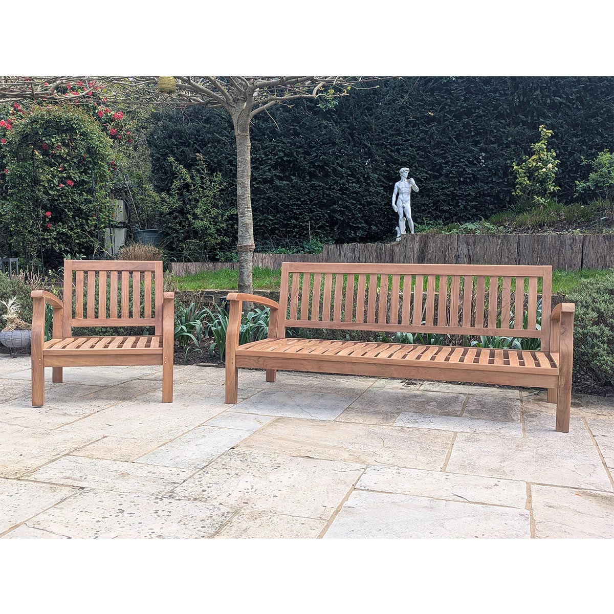 Two wooden benches on a stone patio with a garden background
