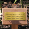 Wooden garden marker and plaque with a inscription on a blurred natural background